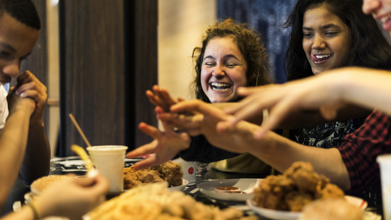 Teens eating fried chicken at a table