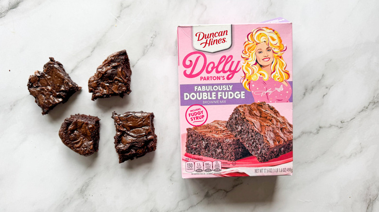 A box of Dolly Parton's Famously Double Fudge Brownie Mix next to four baked brownies