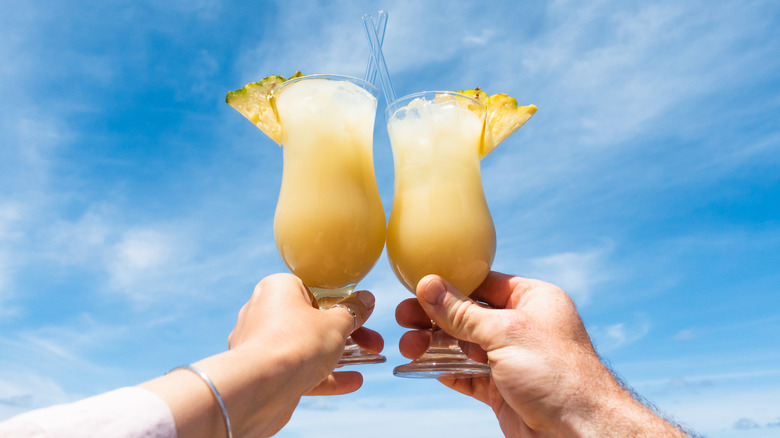 Two foodies hoisting piña coladas