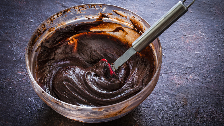 Overhead view of mixing bowl with chocolate cake batter and a spatula.