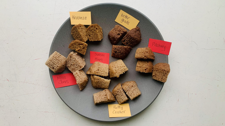 Overhead view of cubes of cut cake mix on a plate with labels for different brands.