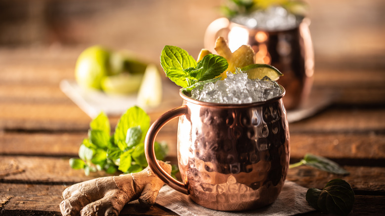 two moscow mule copper mugs with raw ginger roots