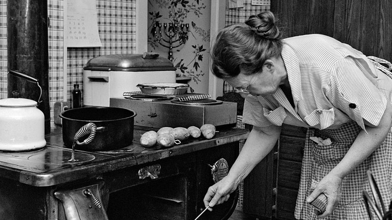 Cook checking on a roast in a vintage oven