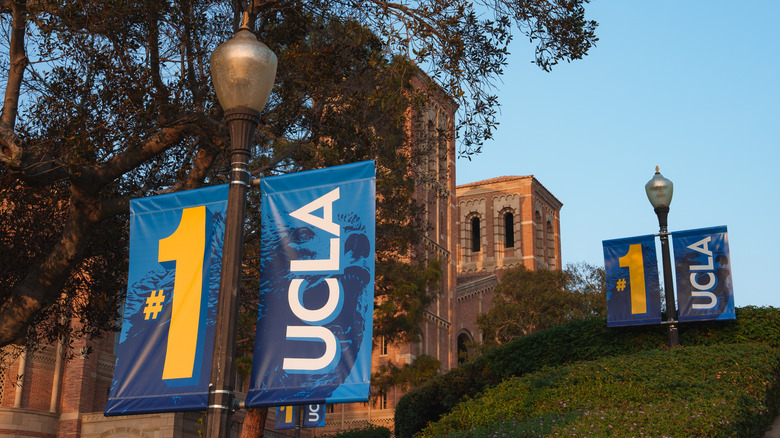 Blue banners spell UCLA celebrating an achievement at UCLA campus with brick building and well maintained greenery