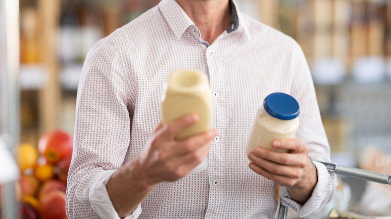 A man compares two jars of mayonnaise
