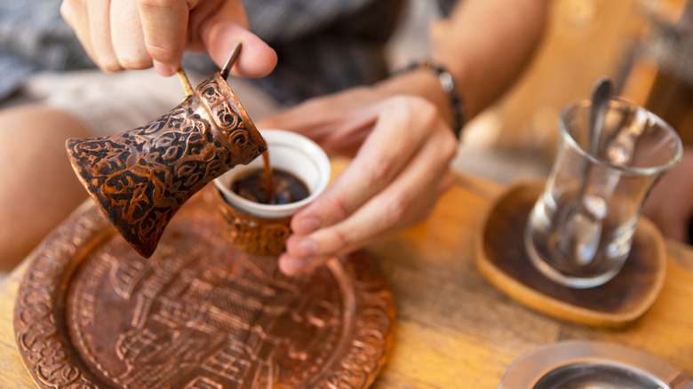 Turkish coffee being poured at a sidewalk cafe.