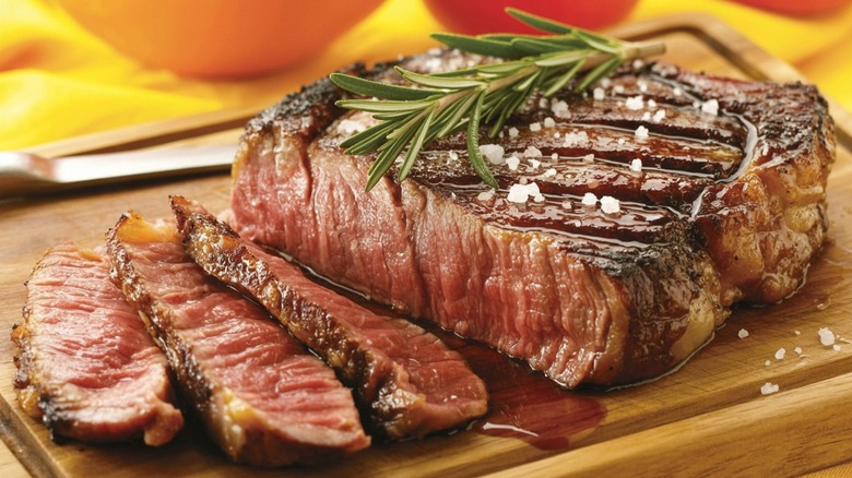 Close-up of a sliced medium rare steak topped with salt and rosemary