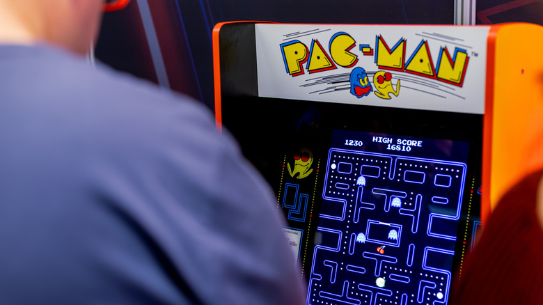 person playing pac-man game in arcade
