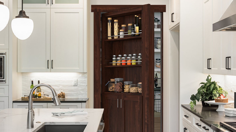 Dark wood Murphy hidden door in white kitchen with door partly opened