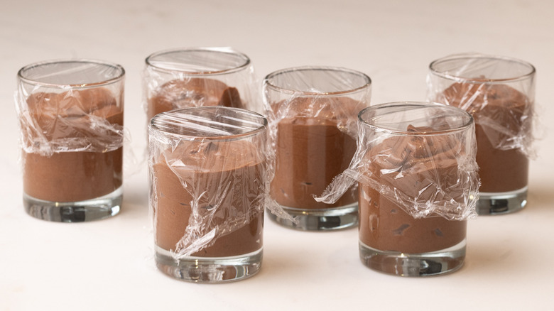Chocolate mousse in glasses covered in plastic wrap