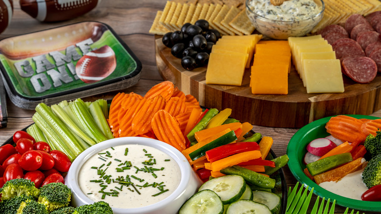 Two platters with cheese dips and dippers next to football plates and decor