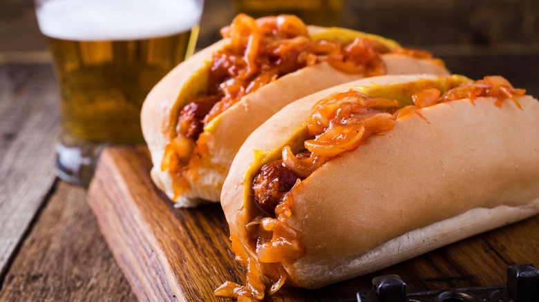 Two hot dogs topped with an onion sauce
