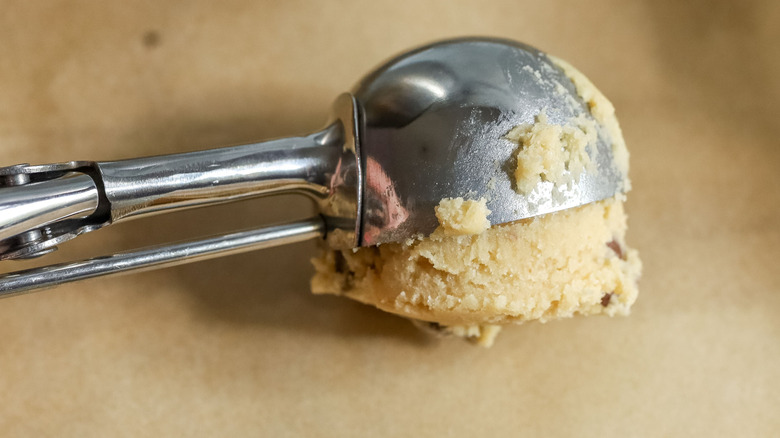 Cookie scoop placing cookie dough ball onto baking sheet