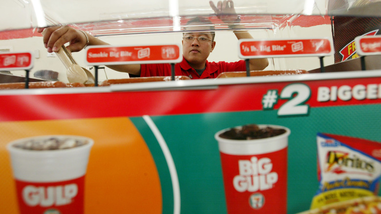 Man grabbing hot dogs at a 7-Eleven location