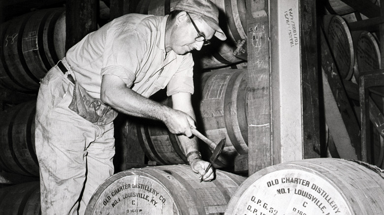 A man opens a barrel with a hammer and pick