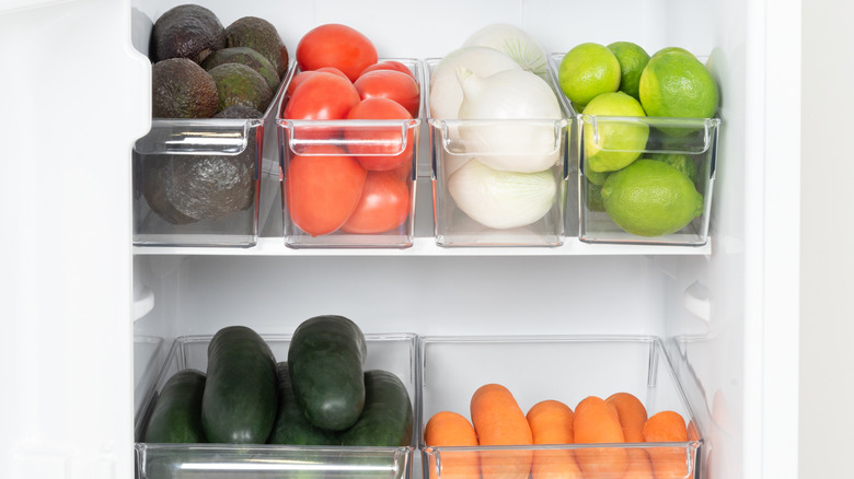 Clear plastic fridge storage bins filled with vegetables