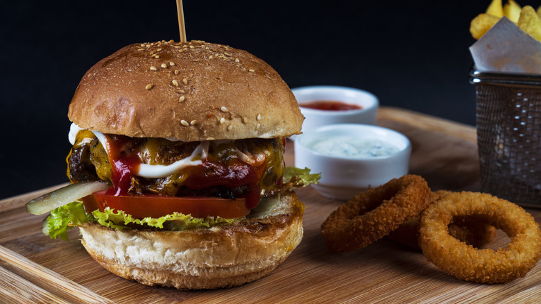 cheeseburger with saucy toppings fries and onion rings
