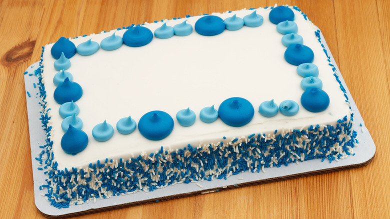 sheet cake with white and blue icing and sprinkles, ready to be cut