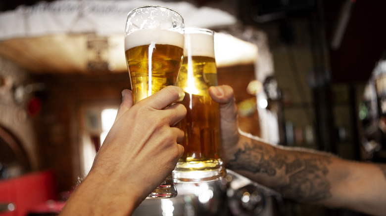 People clinking pint glasses of beer
