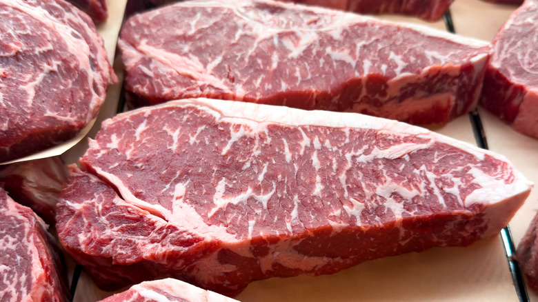 Nicely marbled strip steaks on board