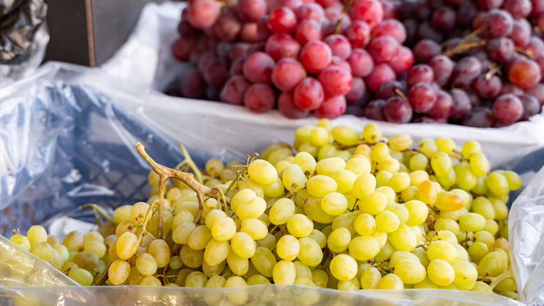Bunches of red and green grapes in bags.