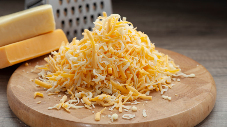 grated cheese with a box grater and blocks of cheese in the background