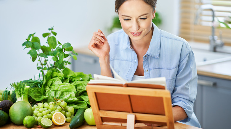 Person reading cookbook on holder in kitchen
