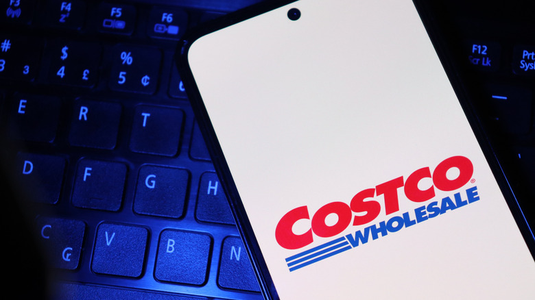 Image of the Costco logo on a smartphone with a computer keyboard.