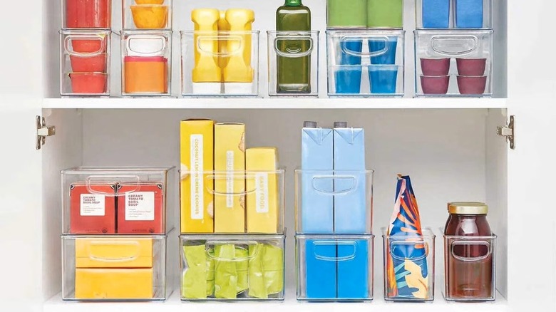 A cupboard full of plastic organizers filled with jars and containers.