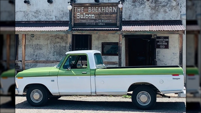 A white and green truck parked outside the Buckhorn Saloon.