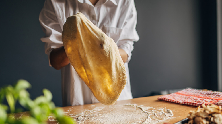 A chef stretching pizza dough on their hands