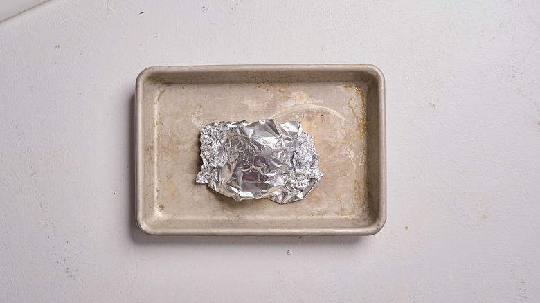 garlic wrapped in foil on a sheet tray