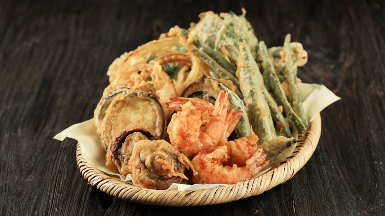 a small mixed basket of tempura featuring mushrooms, shrimp, green beans, and other vegetables