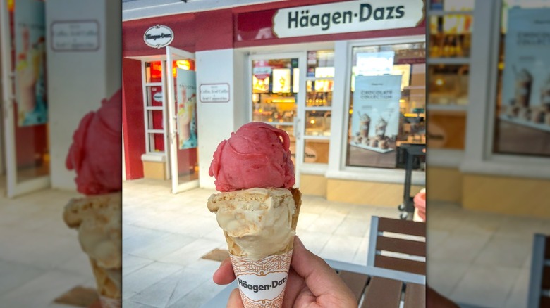 View of person holding ice cream cone outside of Häagen-Dazs store