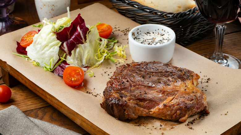 ribeye steak at restaurant with salad and sauce