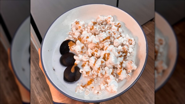 A bowl of milk with popcorn, covered in caramel, and with a said of chocolate buckeyes