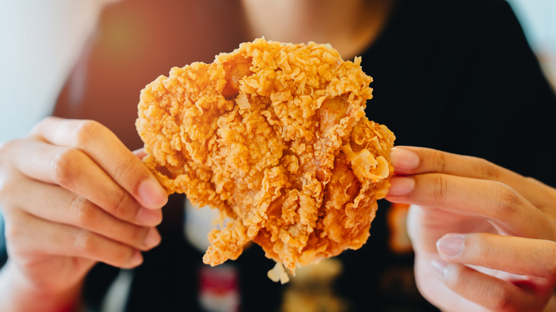 hands holding a piece of fried chicken