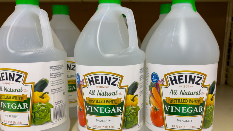 Three bottles of Heinz distilled white vinegar on a supermarket shelf.