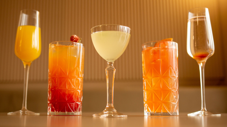 Cocktails, including a traditional mimosa, on a table and warmly lit