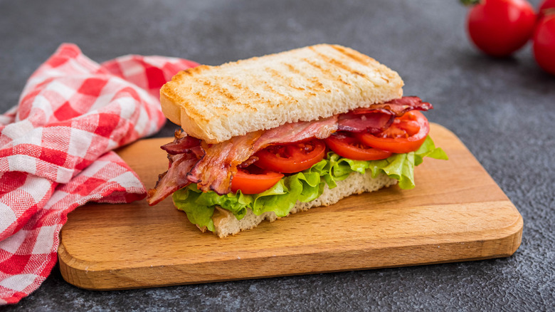 BLT sandwich on cutting board with checkered cloth