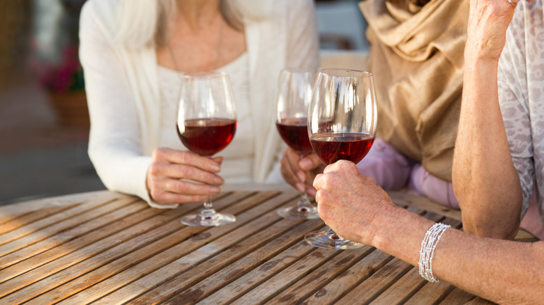 Three older women drinking wine