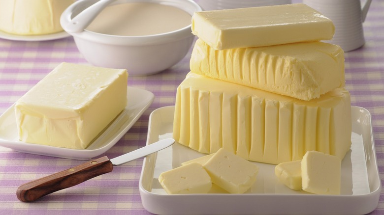Various butter blocks and sticks stacked on plates