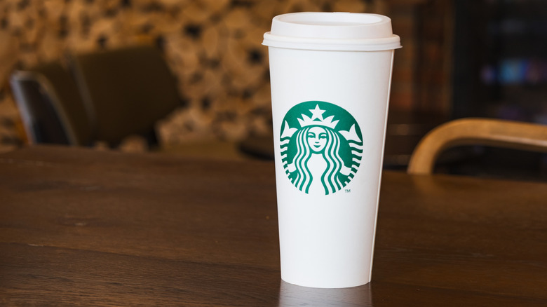 White coffee cup with Starbucks logo sitting on dark wood table