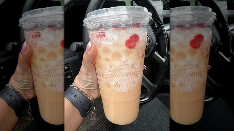 Hand holding large plastic cup of Starbucks Mango Dream drink