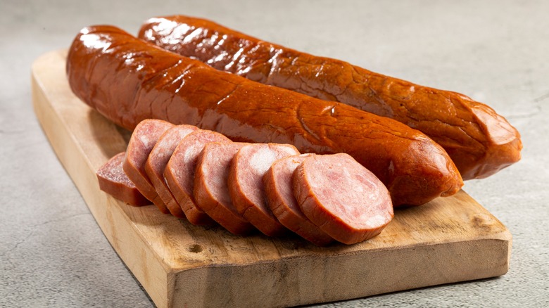 sliced and whole sausage on chopping block