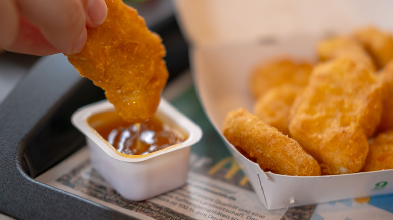Chicken nugget being dipped into McDonald's sweet n' sour sauce