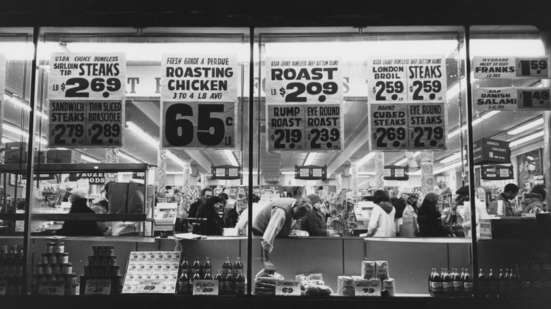 1980s black and white photo of grocery store windows with advertisements