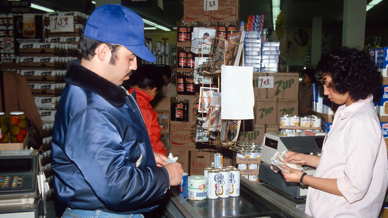1980s era photo of grocery store checakout aisle with female cashier and male customer