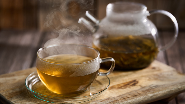 Freshly brewed steaming green tea in a glass cup.