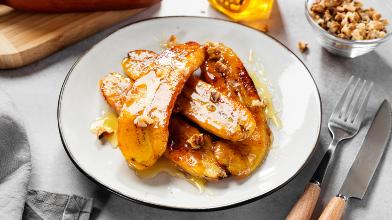 Overhead view of caramelized bananas with nuts and honey on a plate